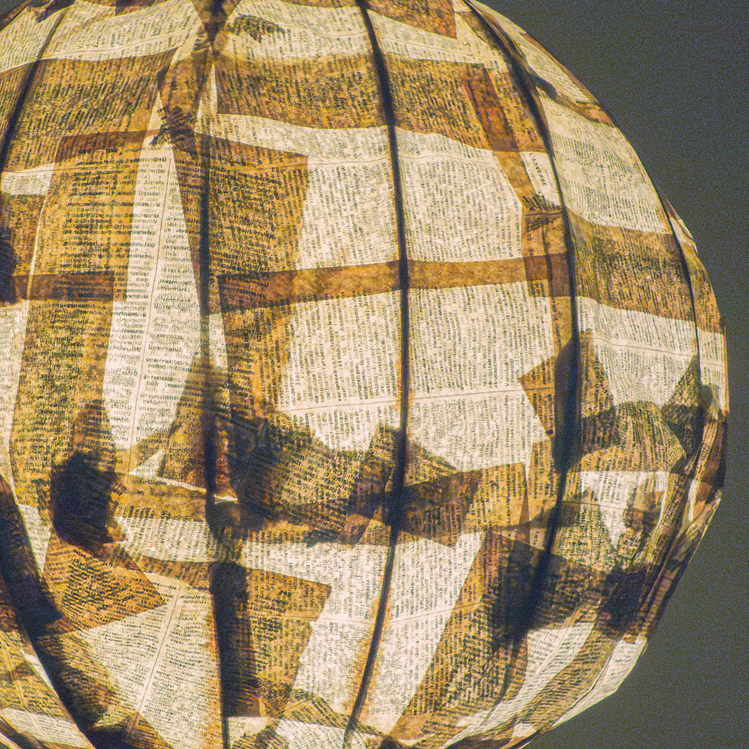 A close-up photo of a papier mâché lamp with a newspaper pattern