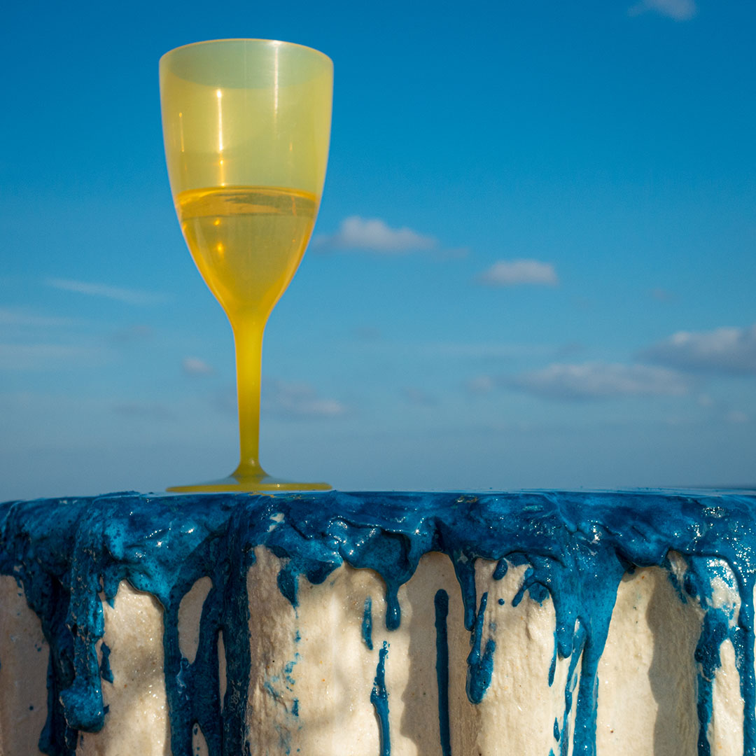 A yellow wine glass on top of the blue cake table