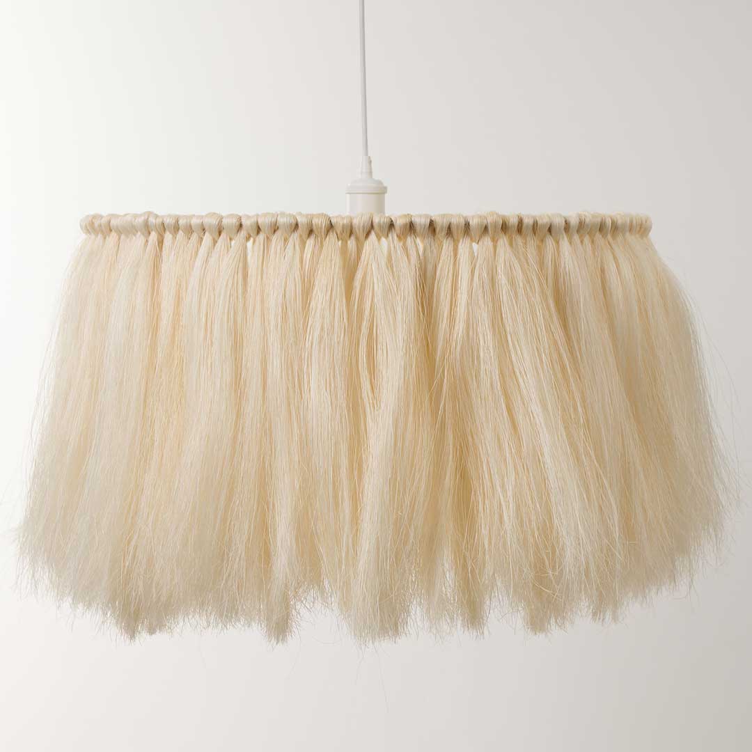 A pendant handmade light with a white fringe hanging from a white wire