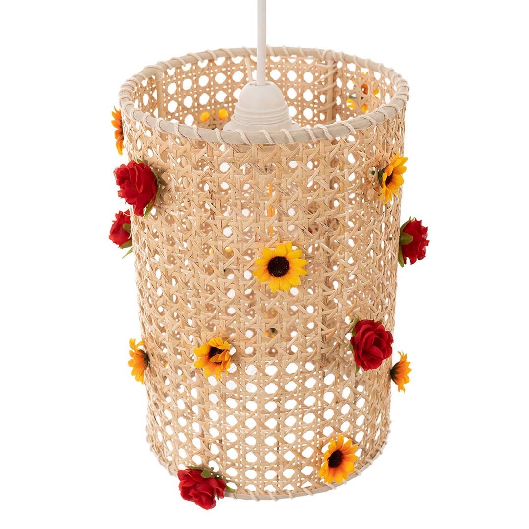 A cylindrical lampshade made of woven rattan, adorned with flowers.