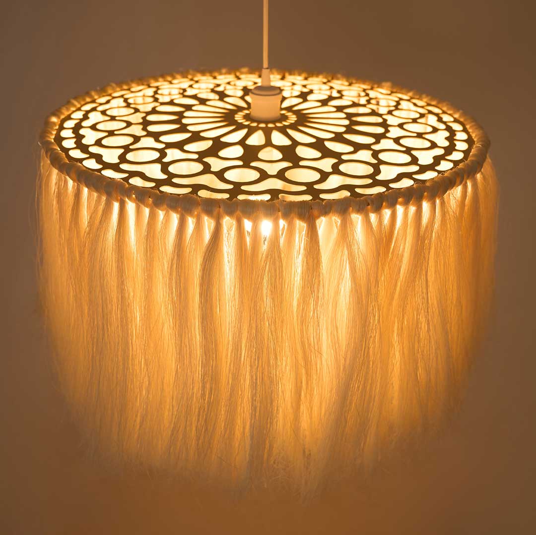 A lit unique boho pendant lamp with a fringed shade made of sisal fibers