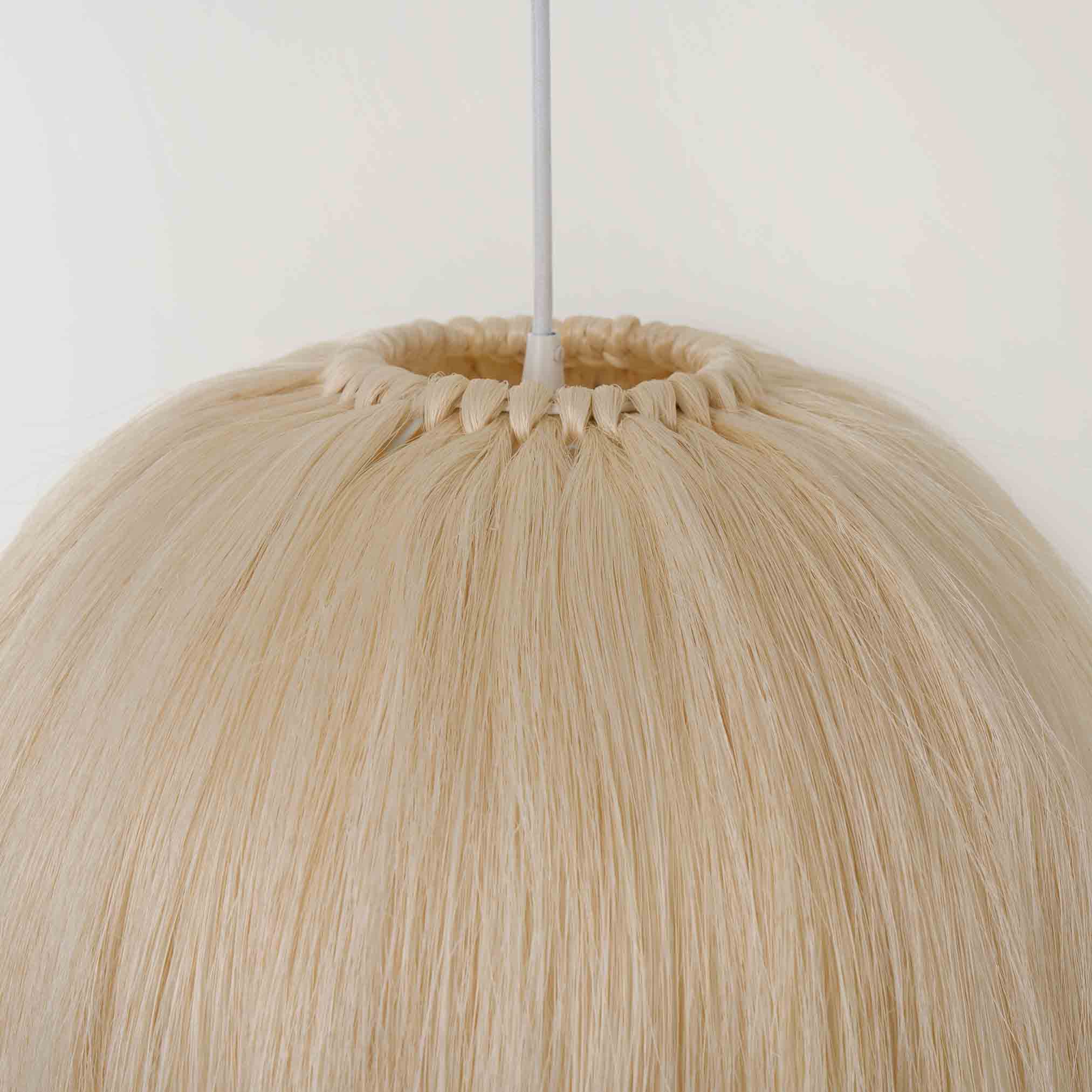 Close-up of handwoven pendant lamp shade made from natural sisal fibers with a round shape and white metal frame