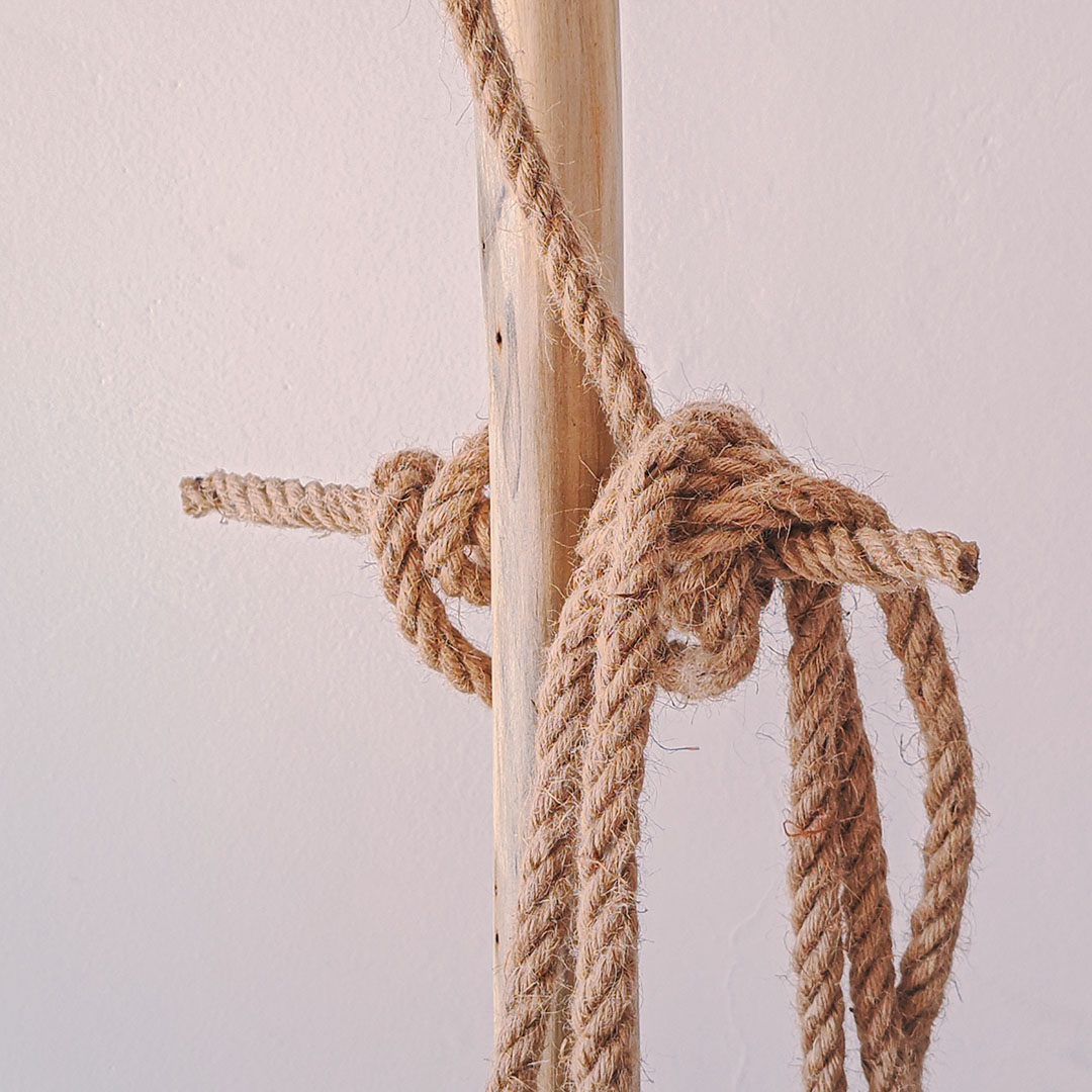 A close-up photo of a thick rope tied in a knot around a wooden pole.