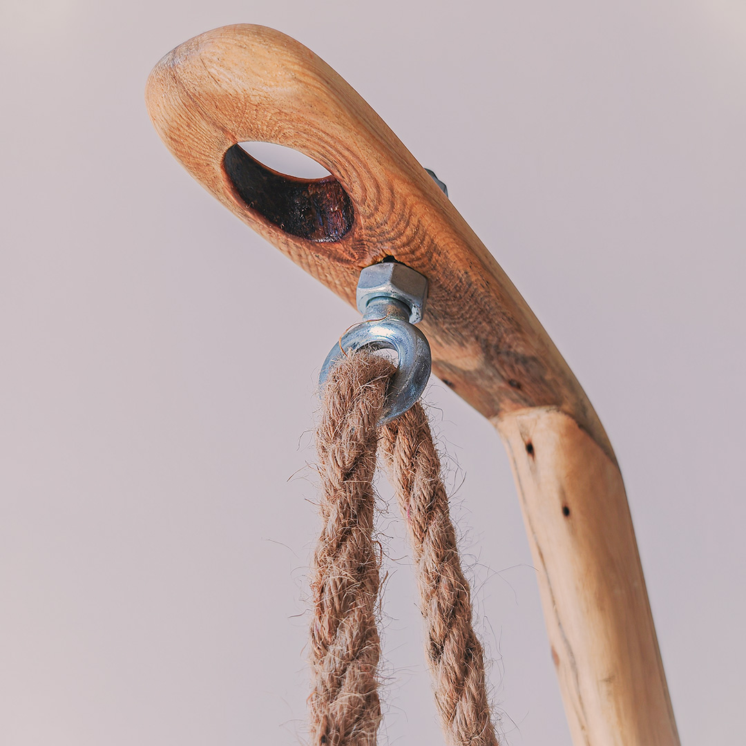 A wooden lamp base with a rope hanging from it.