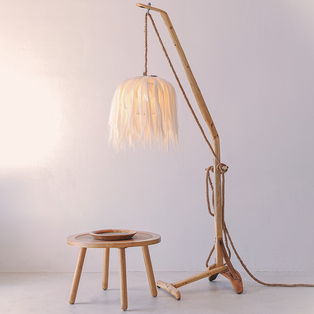 A close-up photo of a rustic wooden table with a sisal wooden lamp standing next to it