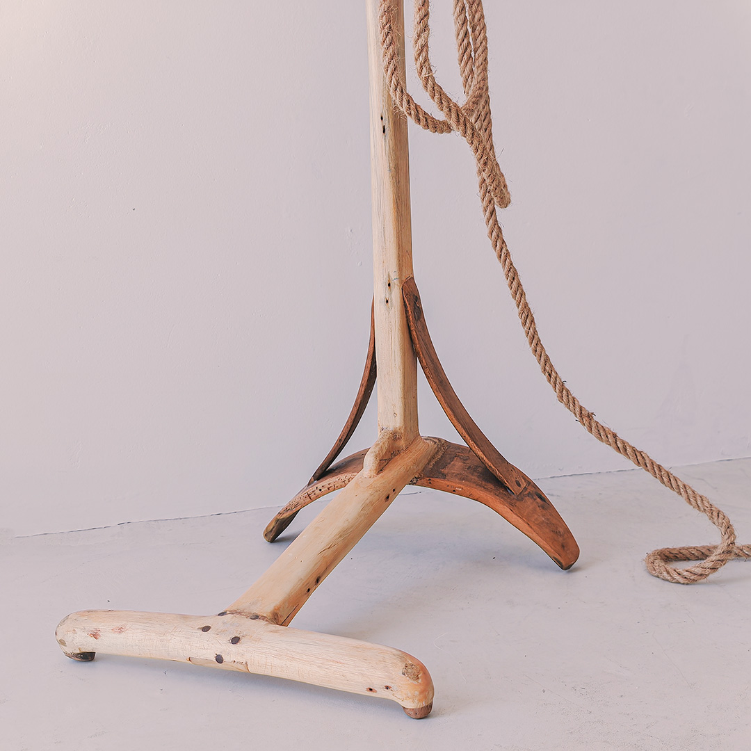 A wooden lamp stand with a rope attached to it, placed on a white background.