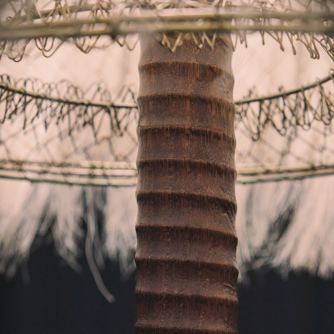 A close-up of a brown wooden lamp base with a small, round metal top